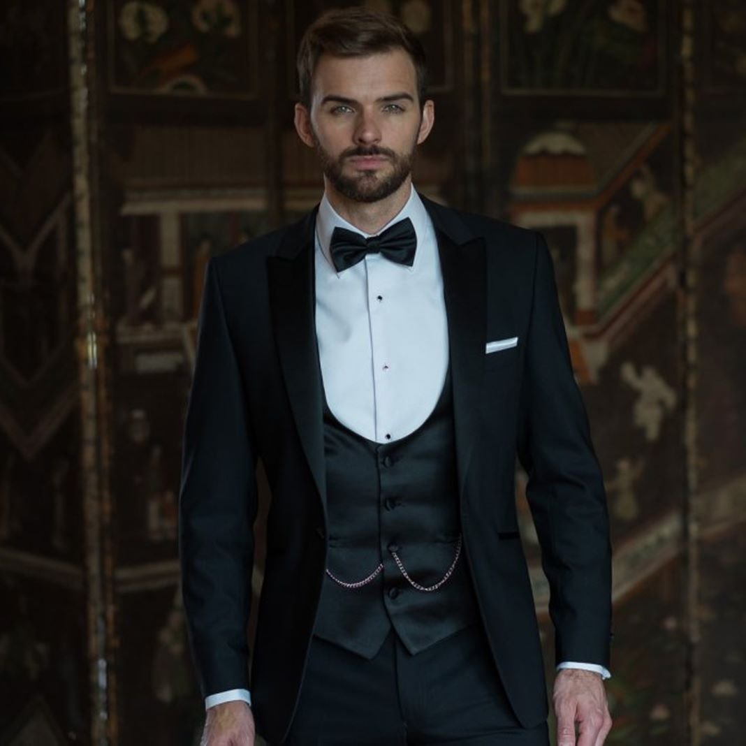 Classic black dinner suit with satin shawl lapels and a bow tie, styled for a wedding reception.