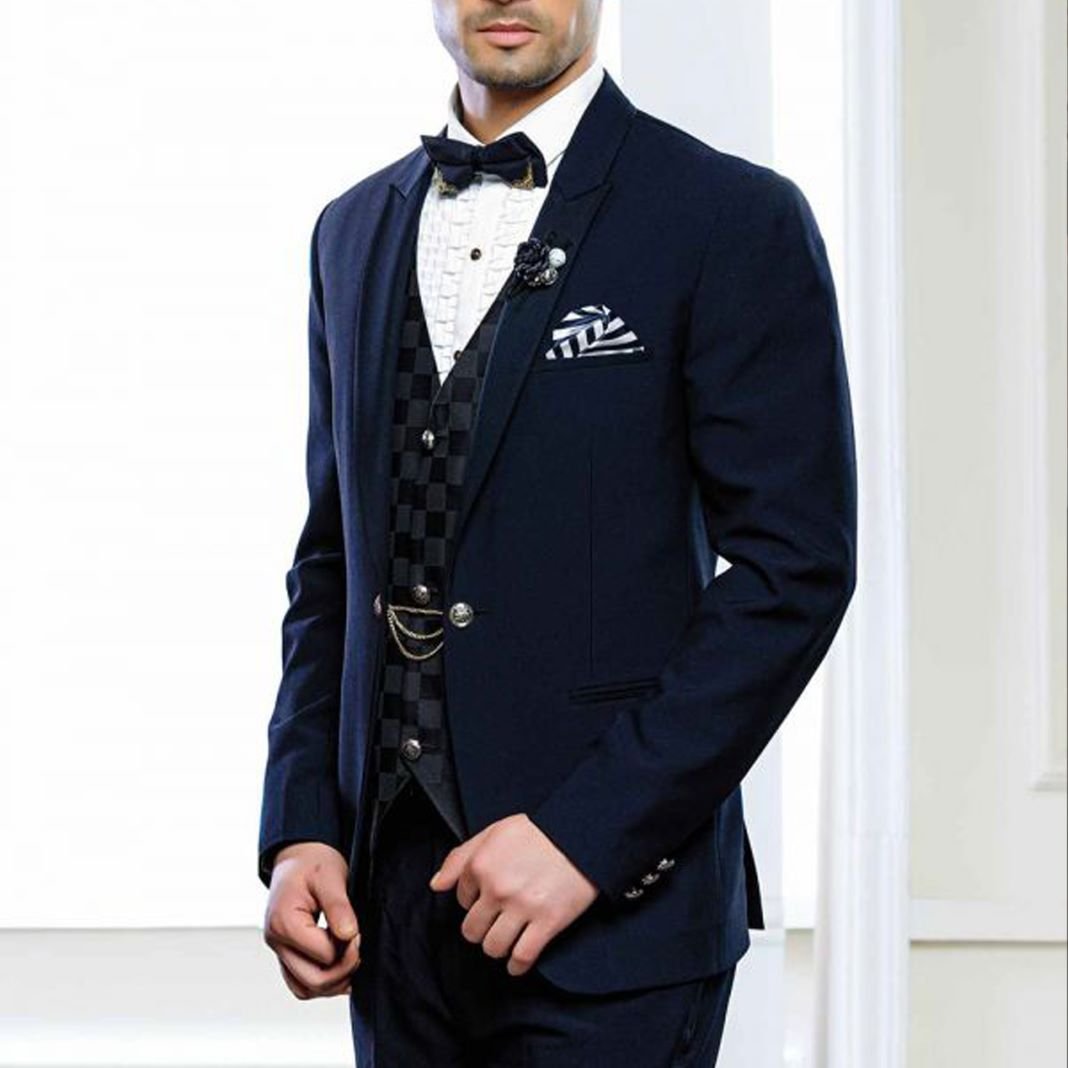 Groom wearing a midnight blue dinner suit with a white dress shirt and black bow tie for an evening wedding