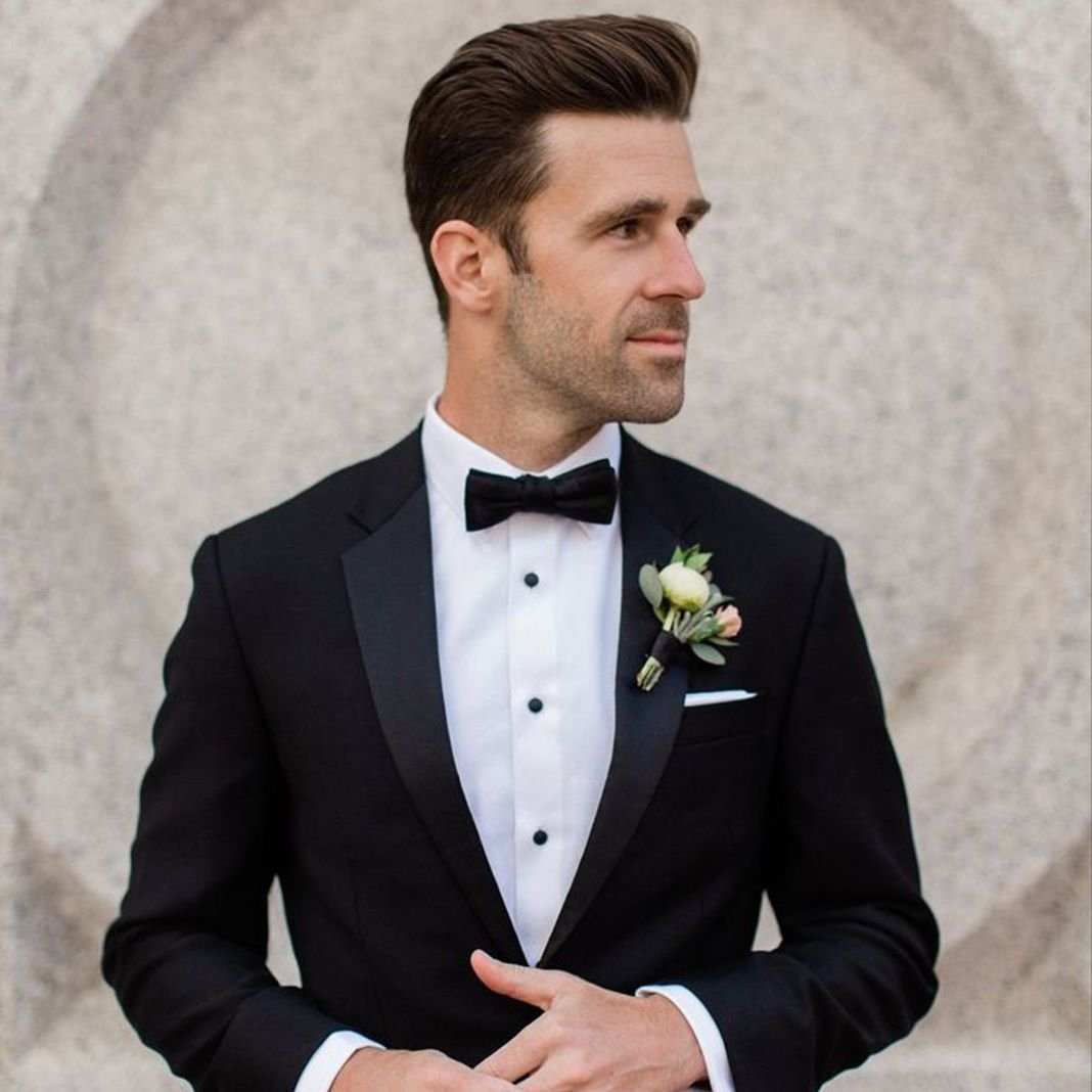 Classic black dinner suit with satin peak lapels, paired with a white shirt and black bow tie for a wedding.